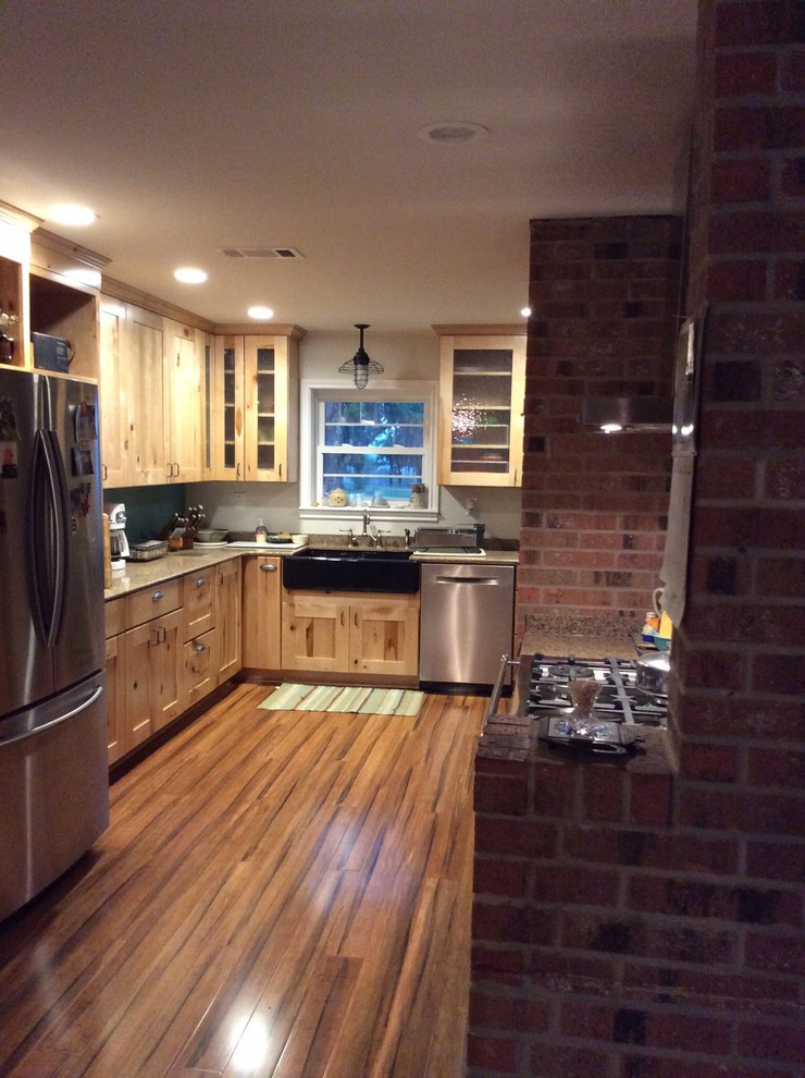 Example of a mid-sized mountain style u-shaped medium tone wood floor enclosed kitchen design in Houston with no island, recessed-panel cabinets, light wood cabinets, quartzite countertops, stainless steel appliances and a farmhouse sink