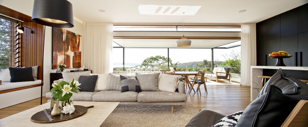 Photo of a large contemporary open concept living room in Sydney with white walls and medium hardwood floors.