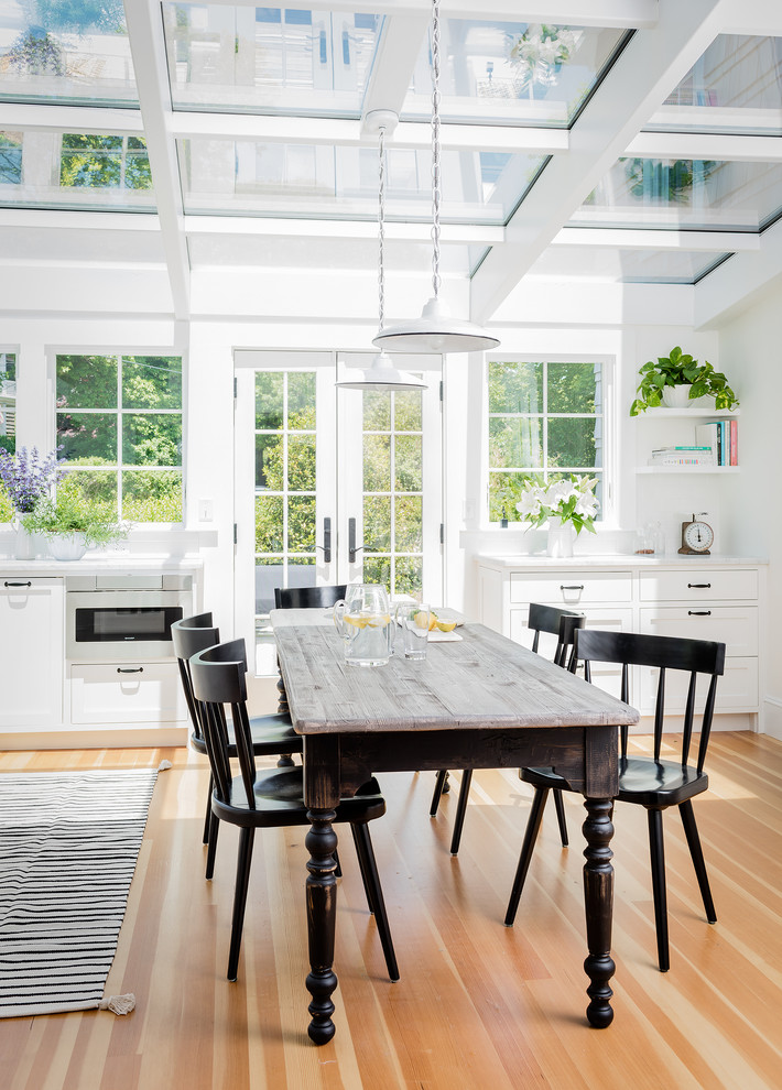 Photo of a beach style kitchen/dining combo in Boston with white walls, medium hardwood floors and beige floor.