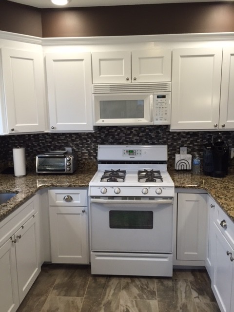 Example of a mid-sized transitional u-shaped porcelain tile eat-in kitchen design in Boston with an undermount sink, recessed-panel cabinets, white cabinets, granite countertops, multicolored backsplash, mosaic tile backsplash, white appliances and a peninsula