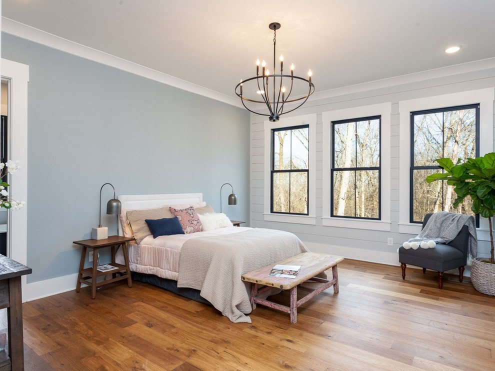 Photo of a large country guest bedroom in Other with multi-coloured walls, medium hardwood floors, no fireplace and brown floor.