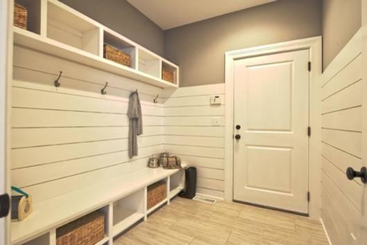 Design ideas for a large modern mudroom in New York with white walls, porcelain floors, a single front door and a black front door.