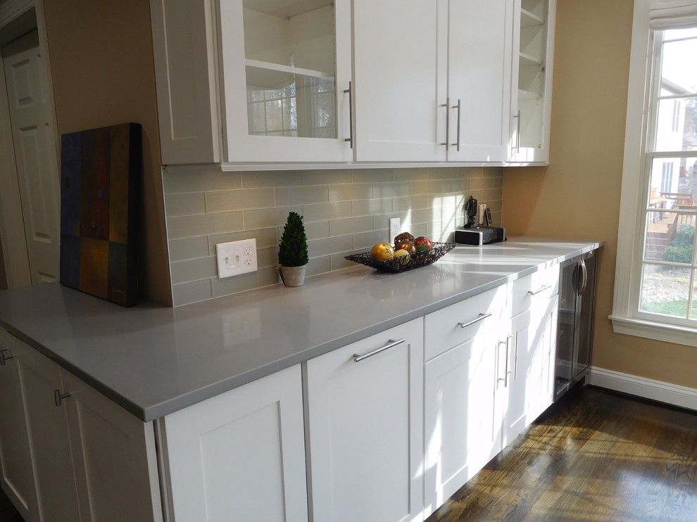 Example of a transitional l-shaped dark wood floor open concept kitchen design in Baltimore with a single-bowl sink, shaker cabinets, white cabinets, quartzite countertops, gray backsplash, glass tile backsplash, stainless steel appliances and an island
