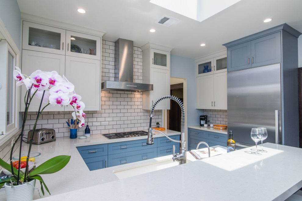 Inspiration for a mid-sized transitional u-shaped ceramic tile and multicolored floor enclosed kitchen remodel with an undermount sink, shaker cabinets, blue cabinets, limestone countertops, white backsplash, subway tile backsplash, stainless steel appliances, a peninsula and white countertops