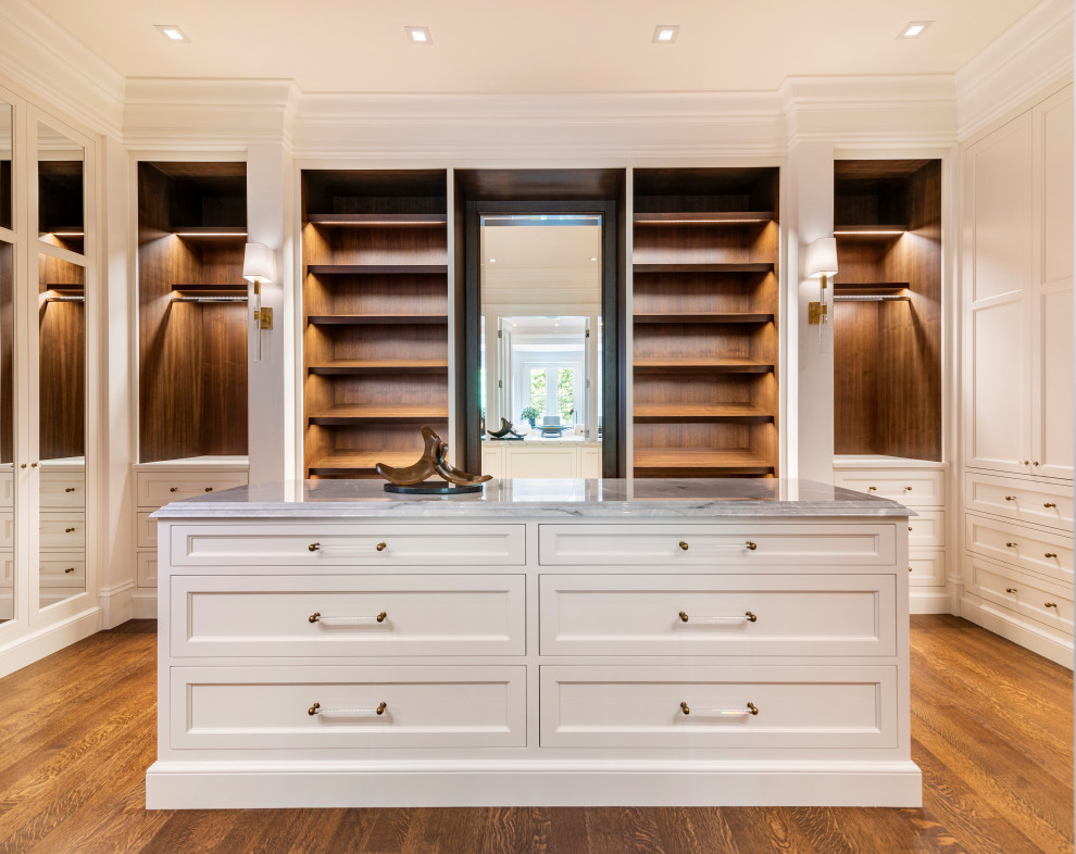 Transitional gender-neutral walk-in wardrobe in Boston with recessed-panel cabinets, white cabinets and medium hardwood floors.