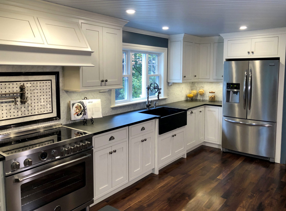 This is an example of a country kitchen in Boston with a farmhouse sink, soapstone benchtops, white splashback, marble splashback, stainless steel appliances, dark hardwood floors and black benchtop.