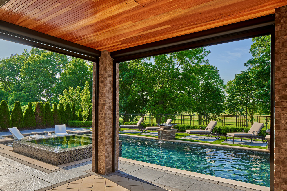 Photo of a mid-sized contemporary backyard custom-shaped pool in Detroit with a hot tub and concrete pavers.