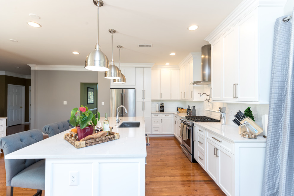 Large transitional l-shaped light wood floor eat-in kitchen photo in DC Metro with an undermount sink, shaker cabinets, white cabinets, quartz countertops, white backsplash, subway tile backsplash, stainless steel appliances and an island