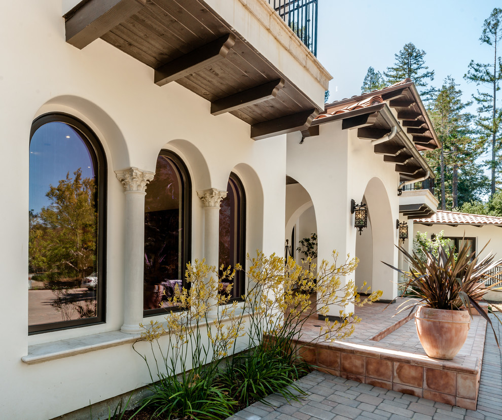 Photo of an expansive mediterranean two-storey adobe beige exterior in San Francisco with a hip roof.