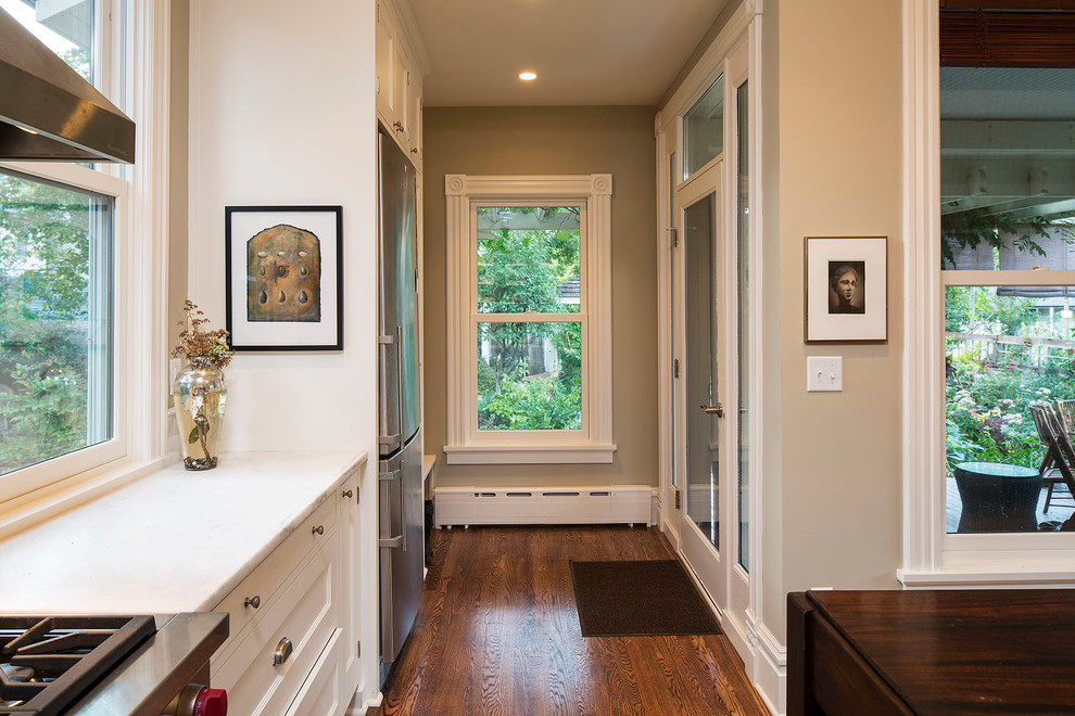 Arts and crafts l-shaped dark wood floor open concept kitchen photo in Minneapolis with an undermount sink, recessed-panel cabinets, dark wood cabinets, marble countertops, gray backsplash, stone slab backsplash, stainless steel appliances and black walls