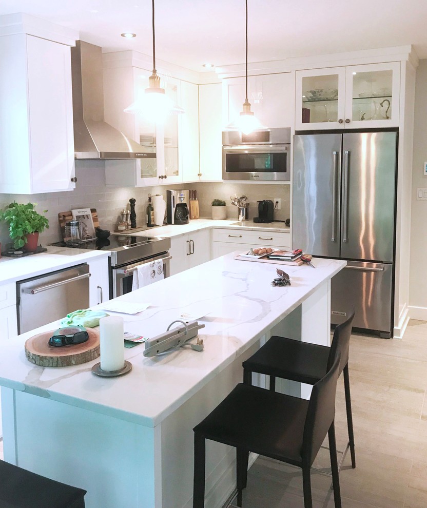 Inredning av ett modernt mellanstort vit vitt kök, med en undermonterad diskho, skåp i shakerstil, vita skåp, bänkskiva i kvarts, vitt stänkskydd, stänkskydd i glaskakel, rostfria vitvaror, klinkergolv i keramik, en köksö och beiget golv