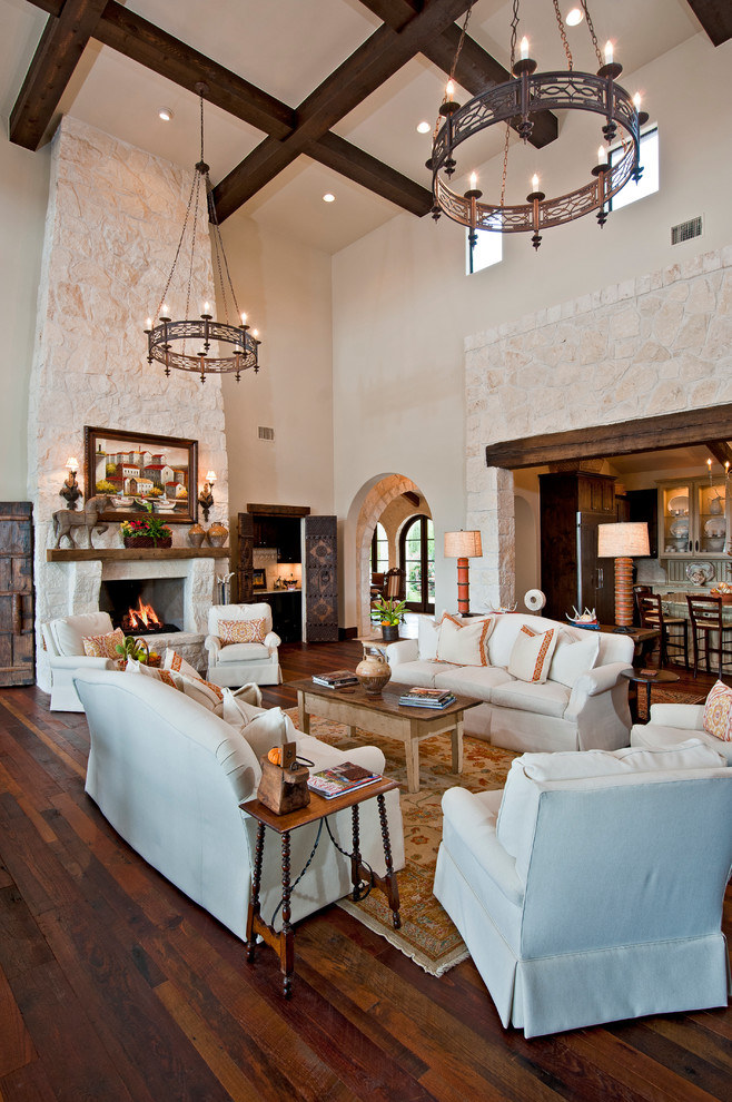 Photo of an expansive mediterranean formal open concept living room in Austin with white walls, medium hardwood floors, a standard fireplace and a stone fireplace surround.