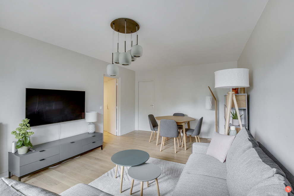 Idee per un soggiorno nordico di medie dimensioni e chiuso con pareti beige, parquet chiaro, TV a parete e pavimento marrone