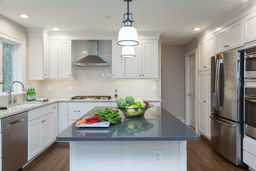 Inspiration for a mid-sized transitional u-shaped dark wood floor enclosed kitchen remodel in Boston with an undermount sink, recessed-panel cabinets, white cabinets, quartz countertops, gray backsplash, subway tile backsplash, stainless steel appliances and an island