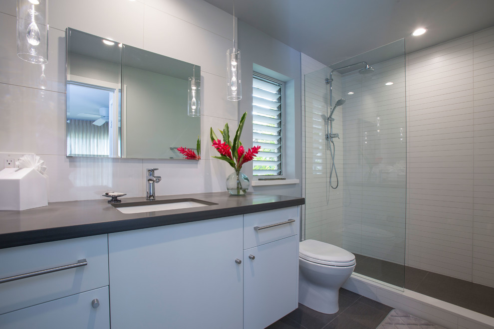 Photo of a transitional bathroom in Hawaii with flat-panel cabinets, white cabinets, an open shower, white tile, porcelain tile, grey walls, porcelain floors, an undermount sink and engineered quartz benchtops.