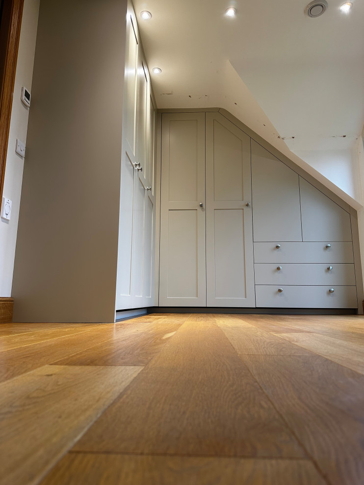 Réalisation d'une grande armoire encastrée tradition en bois clair neutre avec un placard à porte shaker.