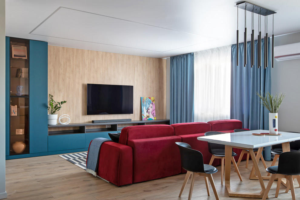 На фото: открытая гостиная комната среднего размера в современном стиле с серыми стенами, полом из ламината, телевизором на стене, бежевым полом и панелями на части стены