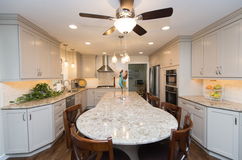 Inspiration for a transitional u-shaped vinyl floor and brown floor eat-in kitchen remodel with an undermount sink, shaker cabinets, quartz countertops, subway tile backsplash, stainless steel appliances and an island