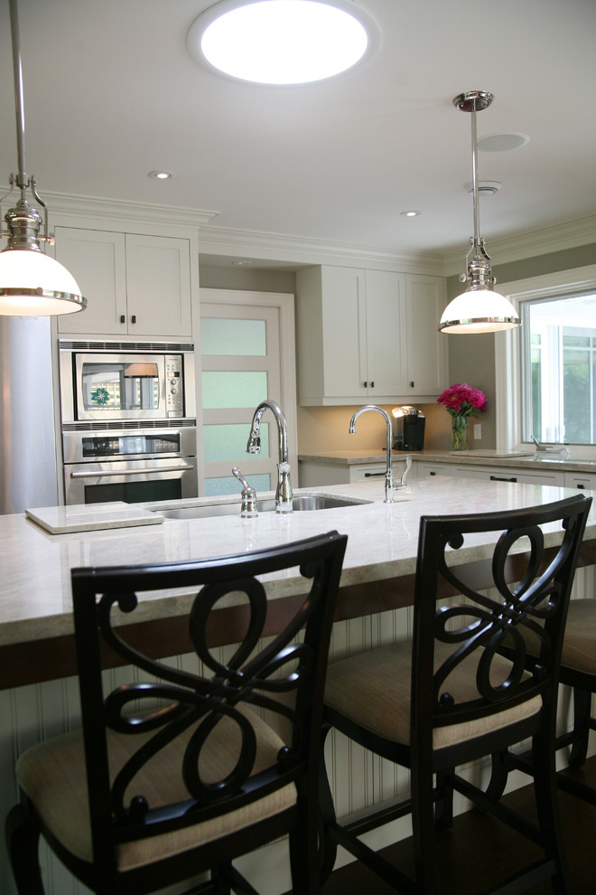 Inspiration for a large transitional l-shaped dark wood floor and brown floor eat-in kitchen remodel in Toronto with an undermount sink, shaker cabinets, white cabinets, stainless steel appliances and an island