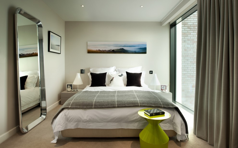 This is an example of a mid-sized contemporary guest bedroom in London with white walls and carpet.