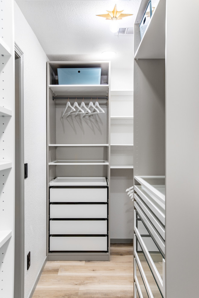 This is an example of a large modern storage and wardrobe in Las Vegas with glass-front cabinets, white cabinets, vinyl floors and beige floor.