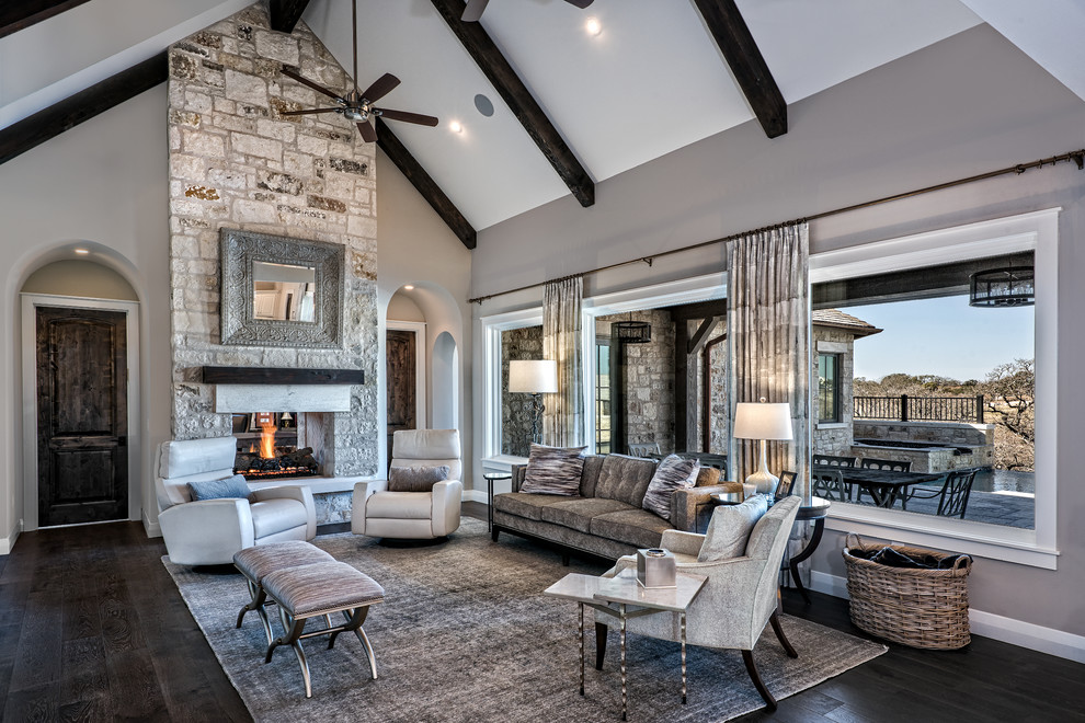 Large transitional open concept family room in Austin with grey walls, dark hardwood floors, a two-sided fireplace, a stone fireplace surround, no tv and brown floor.