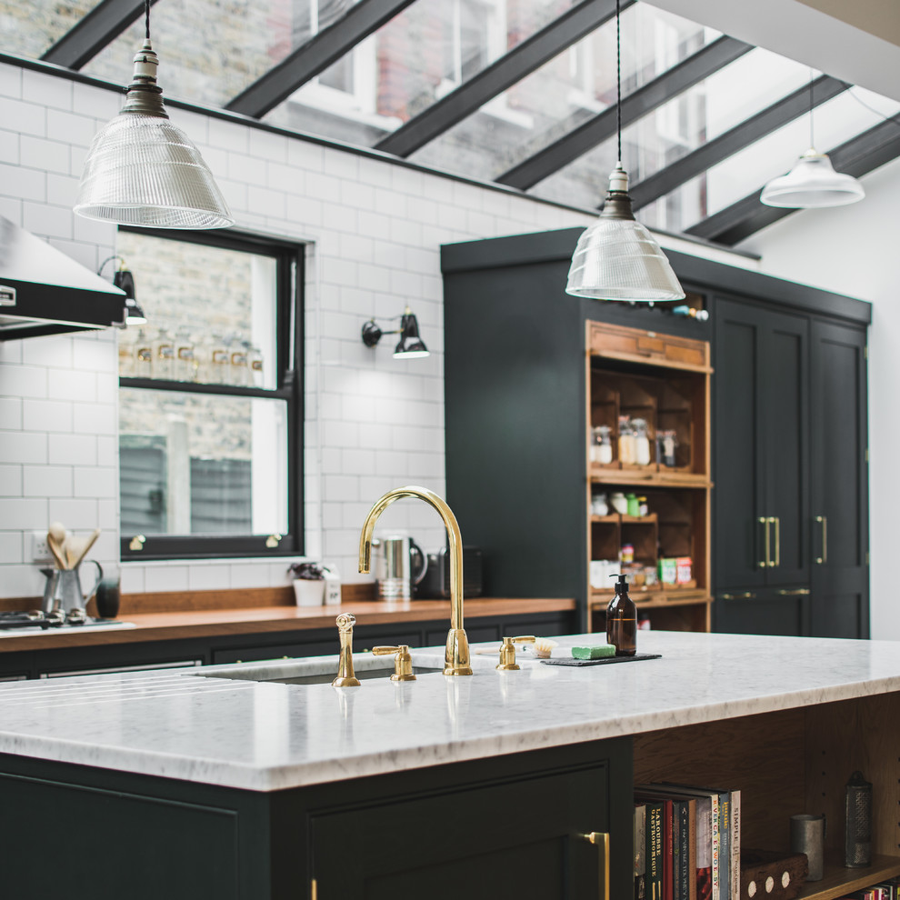 Photo of a large industrial l-shaped eat-in kitchen in London with an undermount sink, shaker cabinets, green cabinets, marble benchtops, white splashback, subway tile splashback, stainless steel appliances and with island.