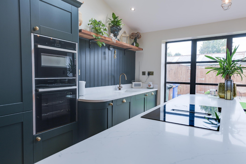 Mid-sized modern single-wall eat-in kitchen in Other with an undermount sink, shaker cabinets, green cabinets, green splashback, shiplap splashback, black appliances, light hardwood floors, with island, brown floor, white benchtop and vaulted.