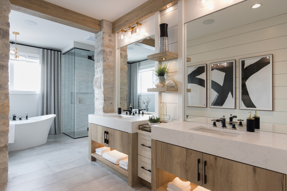 Inspiration for an expansive country master bathroom in Calgary with shaker cabinets, light wood cabinets, a freestanding tub, a corner shower, a one-piece toilet, porcelain tile, white walls, porcelain floors, an undermount sink, engineered quartz benchtops, grey floor, a hinged shower door, white benchtops and planked wall panelling.