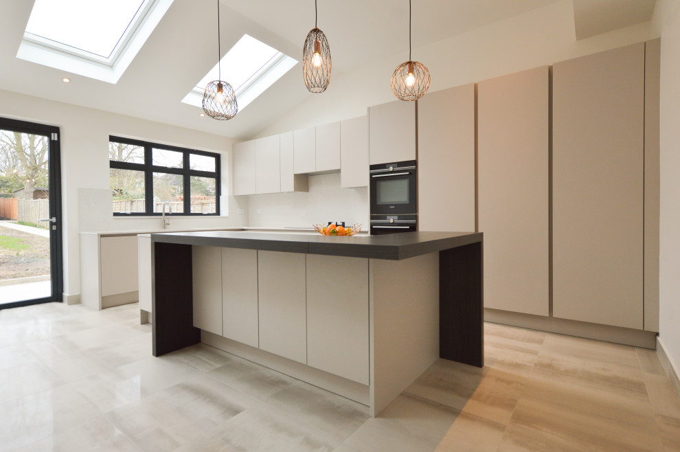Inspiration for a large modern single-wall open plan kitchen in London with a drop-in sink, flat-panel cabinets, quartzite benchtops, stone slab splashback, panelled appliances, porcelain floors and with island.