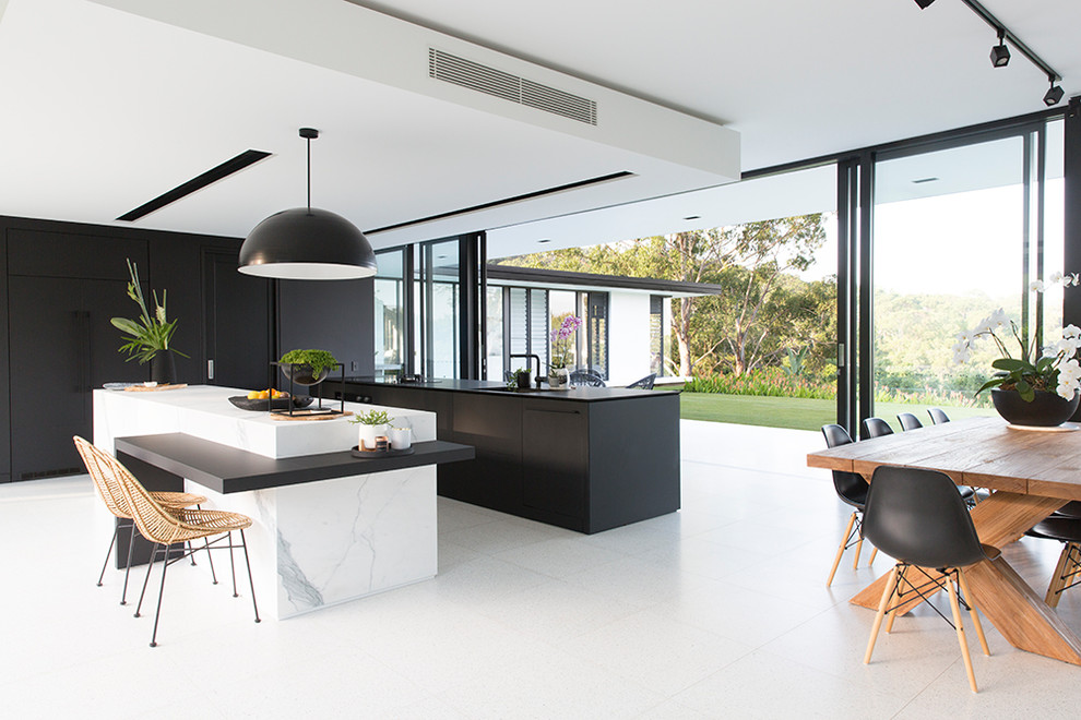 Photo of a modern galley eat-in kitchen in Sunshine Coast with an undermount sink, flat-panel cabinets, black cabinets, panelled appliances, multiple islands, white floor and black benchtop.