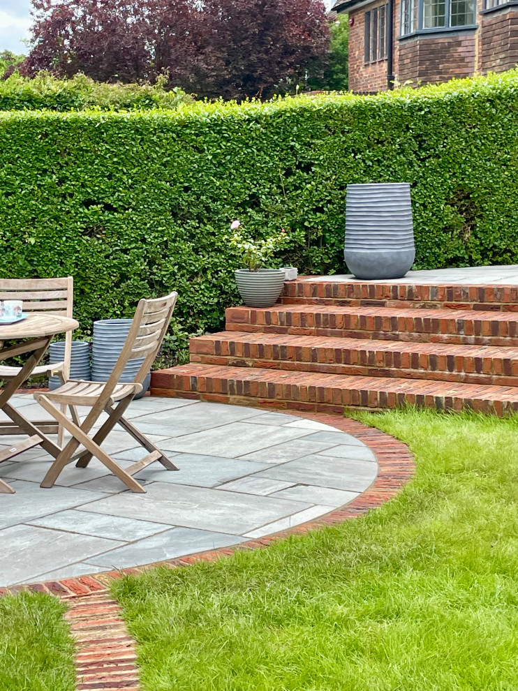 Design ideas for a medium sized classic back patio in London with a potted garden and brick paving.
