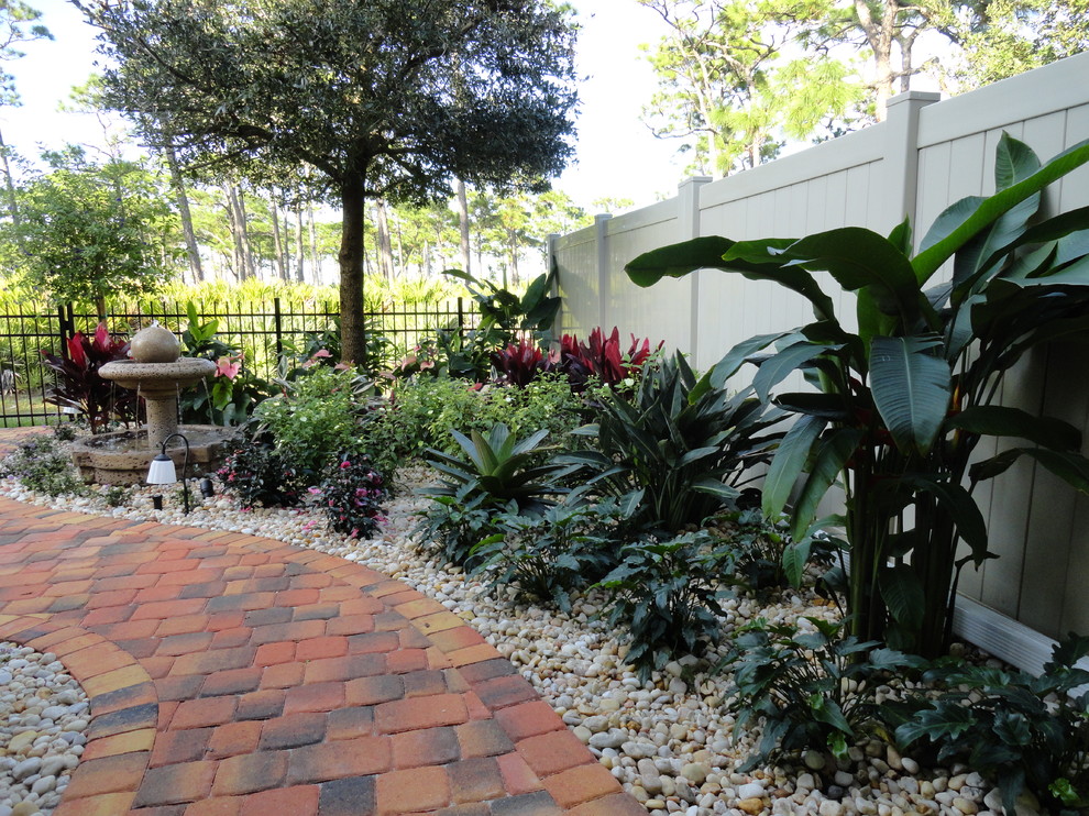 Mid-sized tropical backyard patio in Orlando with brick pavers, a water feature and a roof extension.