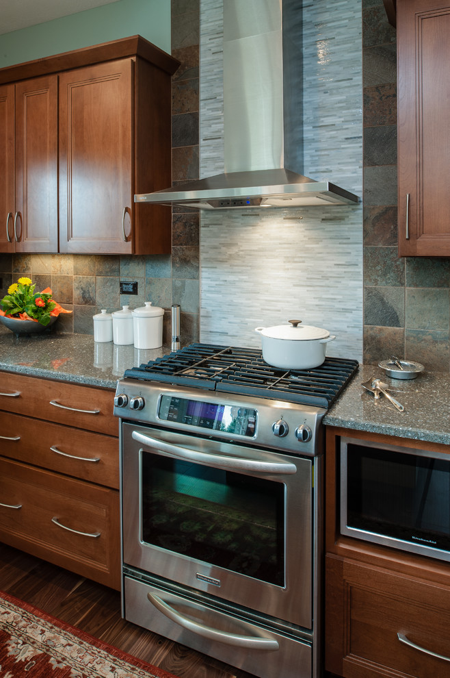 Example of a mid-sized transitional l-shaped medium tone wood floor open concept kitchen design with an undermount sink, shaker cabinets, medium tone wood cabinets, quartzite countertops, gray backsplash, stone tile backsplash, stainless steel appliances, blue walls and an island