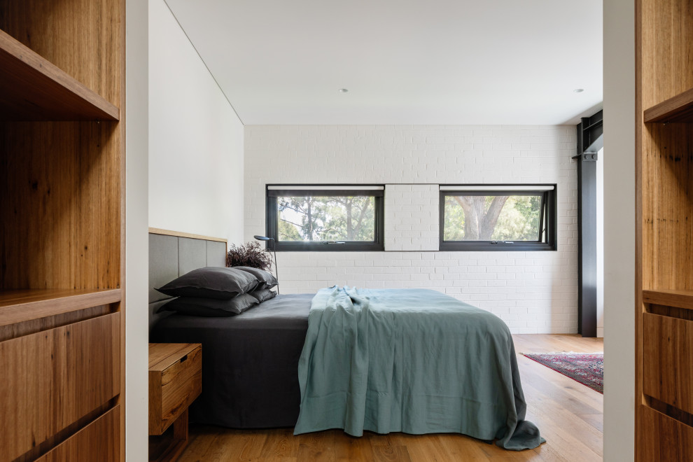 Inspiration for a mid-sized industrial master bedroom in Sydney with medium hardwood floors.