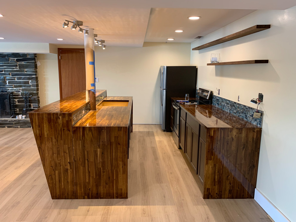 Large midcentury walk-out basement in St Louis with a home bar, beige walls, vinyl floors and brown floor.