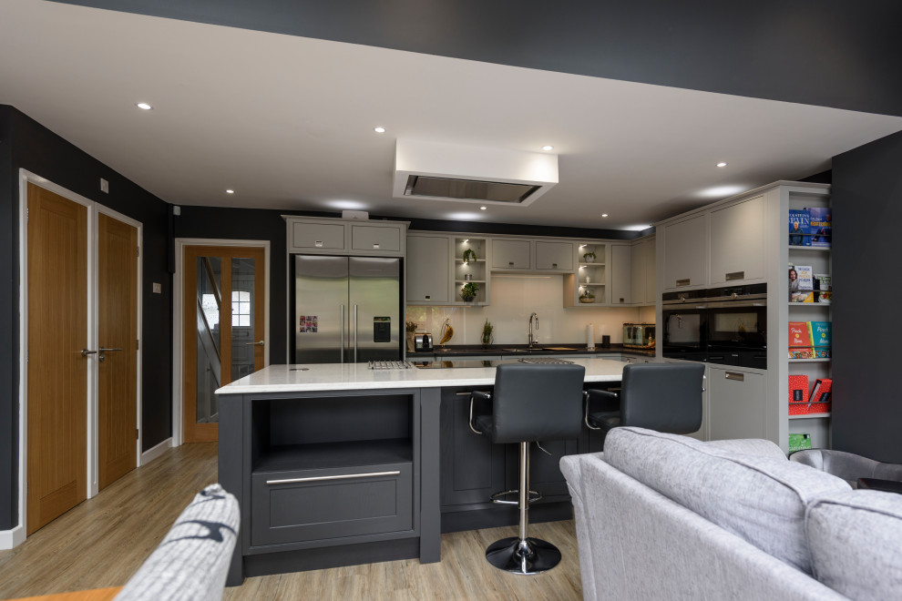 Photo of a large traditional open plan kitchen in West Midlands with a single-bowl sink, quartzite benchtops, white splashback, glass sheet splashback, black appliances and with island.