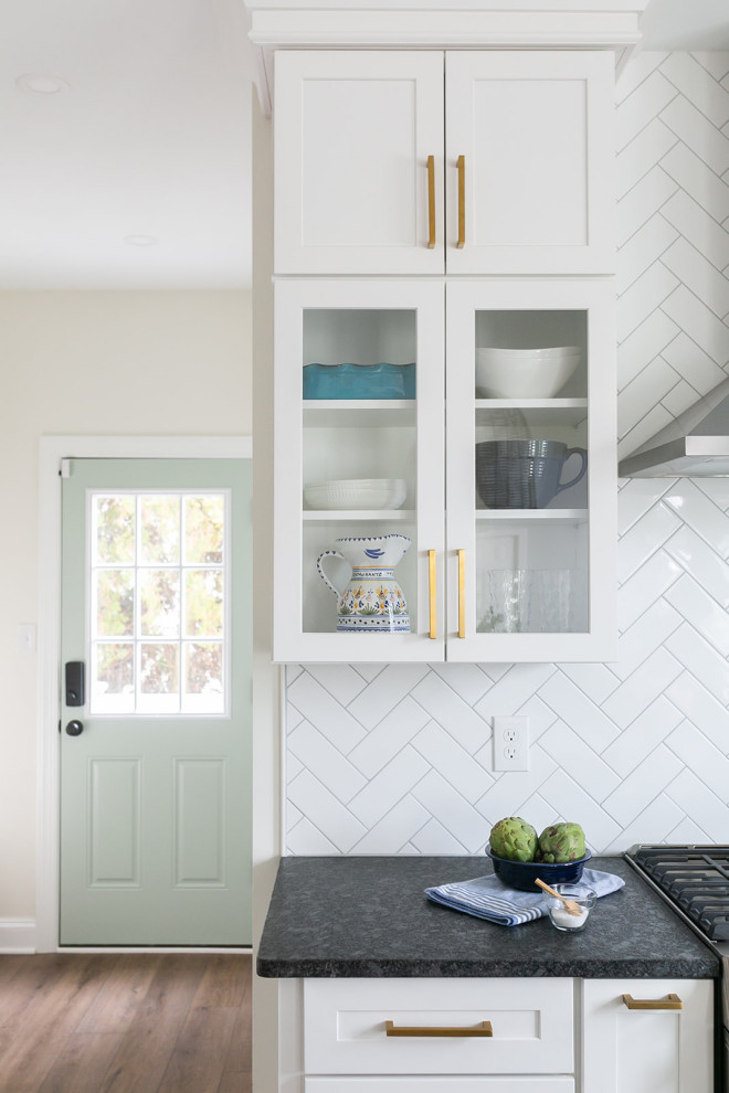 Example of a large transitional l-shaped brown floor kitchen pantry design in Baltimore with a drop-in sink, shaker cabinets, white cabinets, quartz countertops, white backsplash, ceramic backsplash, stainless steel appliances, an island and white countertops