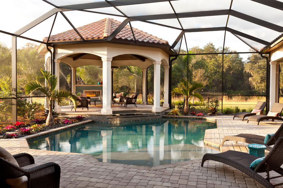 Expansive mediterranean backyard pool in Tampa with brick pavers.