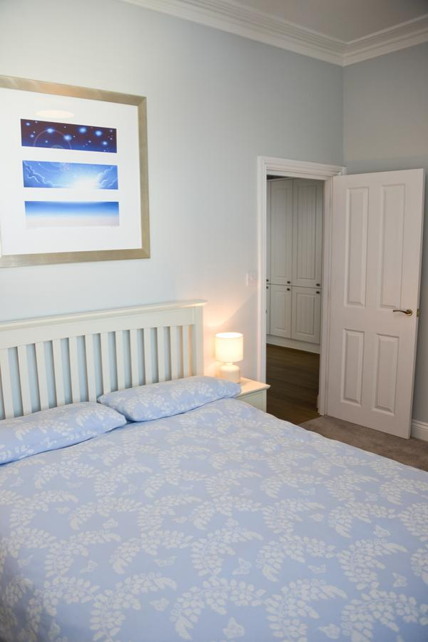 Medium sized coastal master bedroom in Sussex with blue walls, carpet and beige floors.