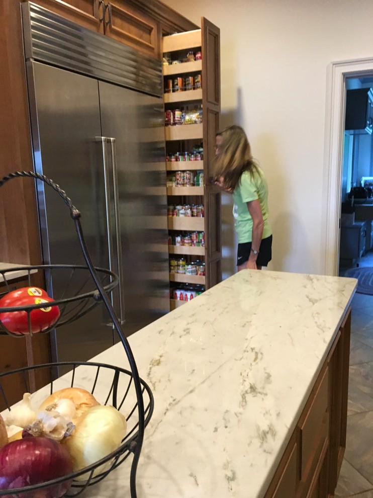 This is an example of a large transitional kitchen pantry in Atlanta with a farmhouse sink, recessed-panel cabinets, medium wood cabinets, quartzite benchtops, white splashback, ceramic splashback, stainless steel appliances, ceramic floors, with island and white benchtop.