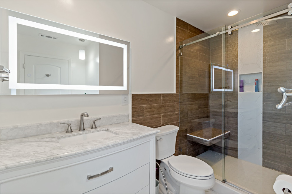 Large contemporary bathroom in San Francisco with flat-panel cabinets, blue cabinets, a drop-in tub, a shower/bathtub combo, a one-piece toilet, marble, an undermount sink, quartzite benchtops, a sliding shower screen, a single vanity and a freestanding vanity.