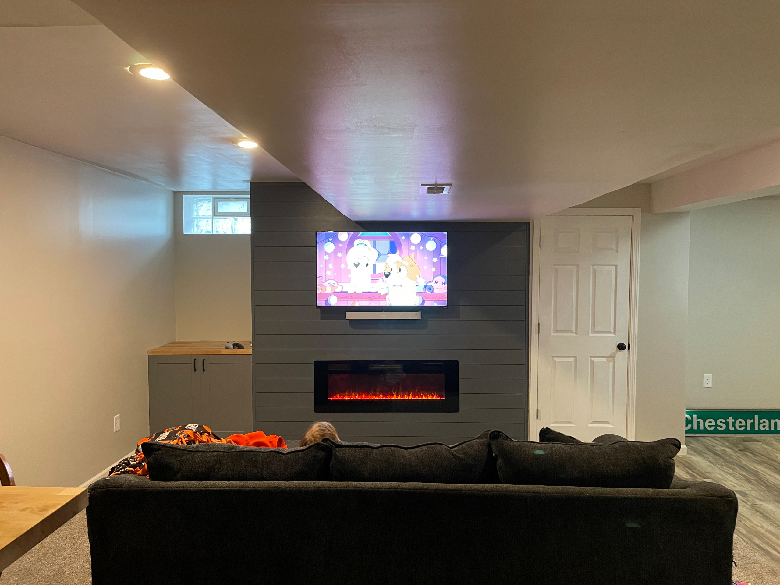 Large trendy underground light wood floor and brown floor basement game room photo in Cleveland with white walls and no fireplace
