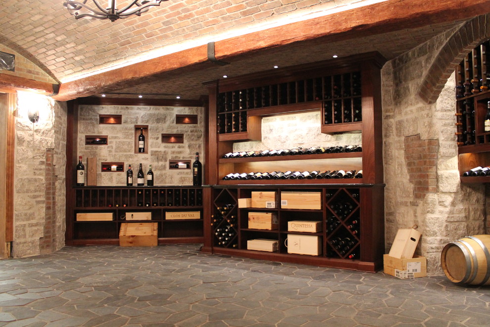 Photo of an expansive mediterranean wine cellar in Ottawa with slate floors, display racks and grey floor.