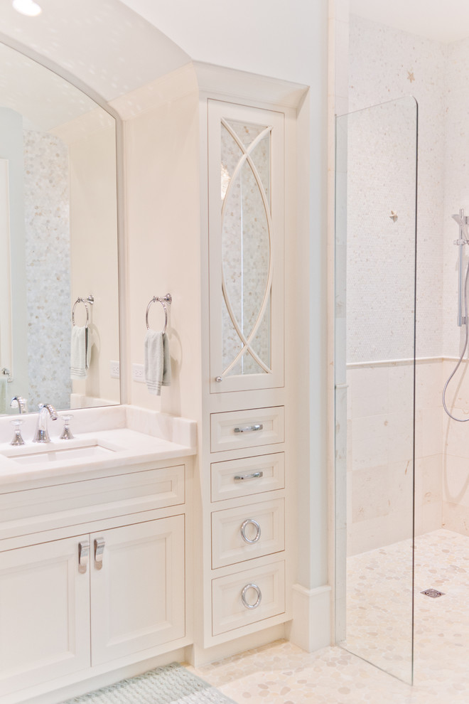 This is an example of a mid-sized beach style master bathroom in Jacksonville with beaded inset cabinets, white cabinets, white tile, white walls, pebble tile floors and marble benchtops.