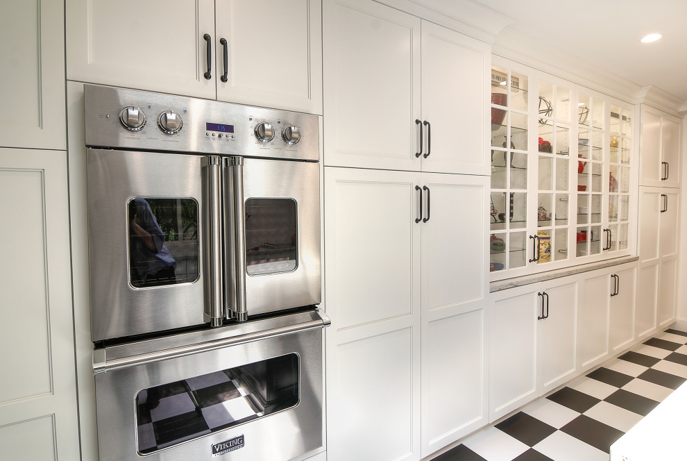 Enclosed kitchen - transitional u-shaped multicolored floor enclosed kitchen idea with a farmhouse sink, glass-front cabinets, white cabinets, granite countertops, white backsplash, subway tile backsplash, stainless steel appliances, an island and beige countertops