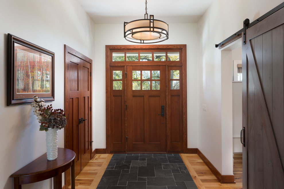 Photo of a mid-sized arts and crafts foyer in Milwaukee with white walls, ceramic floors, a single front door, a dark wood front door and black floor.