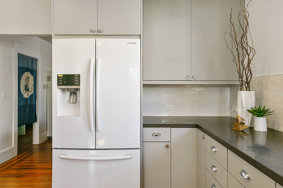 Mid-sized transitional galley light wood floor and beige floor enclosed kitchen photo in San Francisco with an undermount sink, flat-panel cabinets, beige cabinets, quartz countertops, white backsplash, ceramic backsplash, stainless steel appliances and no island