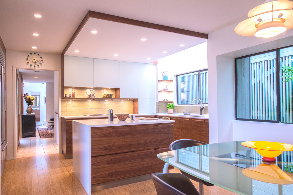 Mid-sized modern u-shaped eat-in kitchen in Vancouver with an undermount sink, flat-panel cabinets, dark wood cabinets, quartz benchtops, green splashback, glass tile splashback, stainless steel appliances, bamboo floors, with island and beige floor.