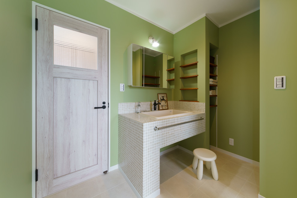 This is an example of a scandinavian powder room in Other with open cabinets, green walls, tile benchtops and beige floor.